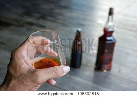 Local whiskey in a glass with bottle of herbal liquor in Thailand.