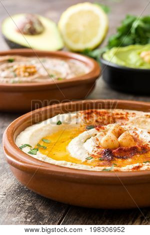 Different hummus bowls. Chickpea hummus, avocado hummus and lentils hummus on wooden table