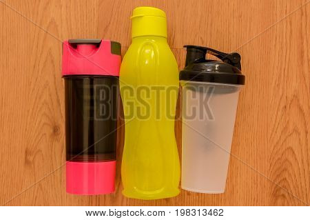 Athlete's set with three bottles of water, in a row on wooden background.