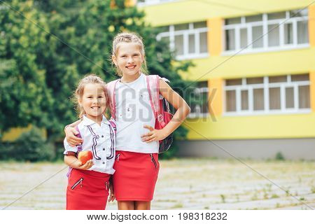 Two cute sisters go to school. The elder sister leads the youngest first time in the first class. Back to school.