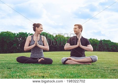 Man and woman practice acro yoga in the park meditation