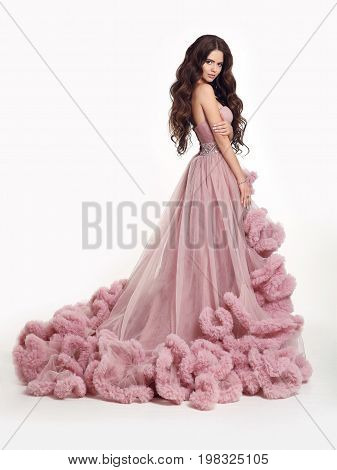 Beautiful Lady in luxury lush pink dress. Fashion brunette woman in gorgeous long gown posing isolated on white studio background.