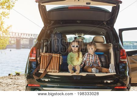 Travel by car family together brother and sister sitting in a trunk