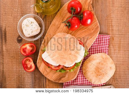 Puccia bread with mozzarella and tomato on cuttingboard.