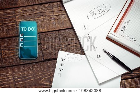 Paper And Electronic To Do Lists On Wooden Surface Top View. Memo Planning Technology Concept