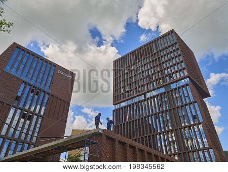 MOSCOW, JUN,28. 2017: Veiw on almost done new loft style modern building made of brown bricks with big wide windows EGODOM. Constraction works almost done. Workers on wall. Modern loft architecture