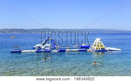 BRELA, CROATIA - 6 JULY, 2017: Aquapark on the sea with resting tourists in Brela, Croatia.