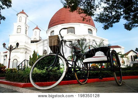 Classic bycicle at the park in the front of ancient church called 