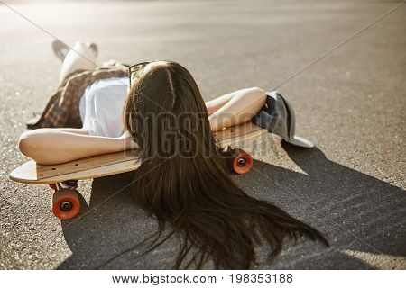 Female skateboarder laying on her lonboard on a sunny day relaxing