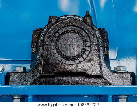 Black ball bearing housing on a blue machine. End of drive shaft visible. Lubrication nipple on top of housing.