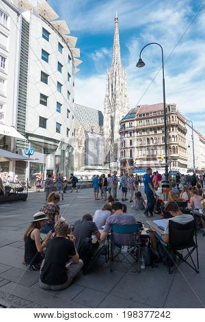 Vienna Austria - July 31 2017: Stephansplatz in Central Vienna with famous St. Stephens Cathedral. Students sitting on the street and drawing the church.