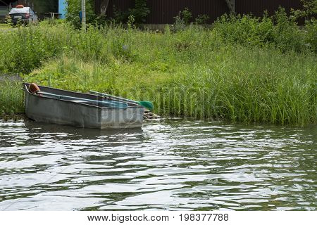 old small boat with oars is docked on the shore of the river the grass water countryside