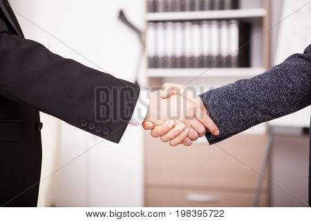 Close up Business partners shaking hands in the office. Two businessman in formal suits shaking hands in corporate office eviroment
