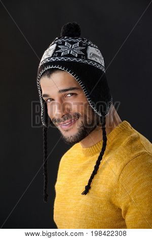 Portrait of smiling man in wooly hat against black background