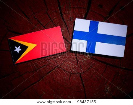 East Timorese Flag With Finnish Flag On A Tree Stump Isolated