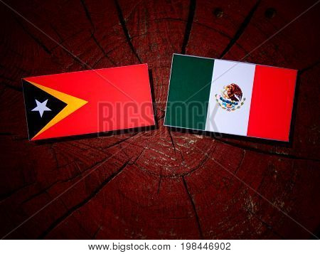 East Timorese Flag With Mexican Flag On A Tree Stump Isolated