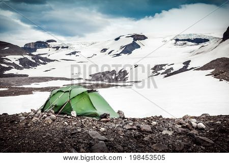 Camping with tent in snowy mountains and glaciers of Iceland. Stormy winds in Porisdalur. Vintage style image.