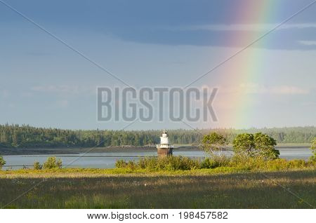 Rainbow near Lubec Channel lighthouse during low tide in northern Maine.