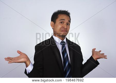 Photo image of a handsome attractive young Asian businessman with i don't know gesture isolated on white