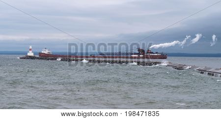 Leaving Marquette, Michigan, a fully-loaded ore carrier is about to pass the Presque Isle Breakwater Light and head into the open waters of Lake Superior.