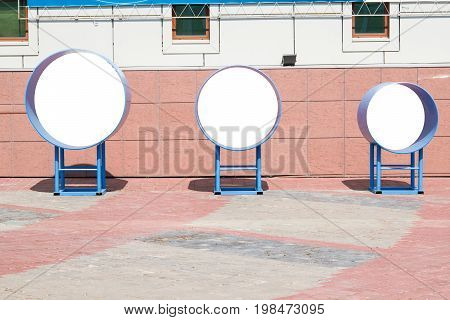 Mock up three metal circle on a stand on the street near the building for advertisement, mocap