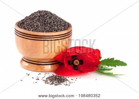 Poppy seeds in a wooden bowl with a flower.