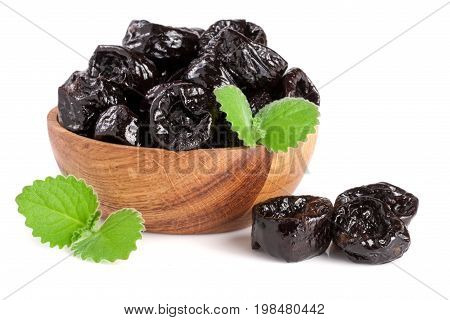Dried plums or prunes with a mint leaf in wooden bowl isolated on white background.