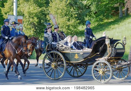 STOCKHOLM SWEDEN - JUN 06 2017: The swedish queen and king Silvia and Carl Gustaf Bernadotte waiving to the audience from the royal coach on their way to celebrate the swedish national day.