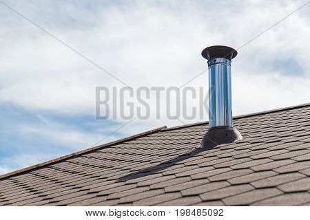 Chimney pipe from stainless steel on the roof of the house.