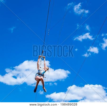 Ukraine Migea - July 30 2017: Zipline. A view of a man sliding on a steel cable against a beautiful blue sky with white clouds. Extreme and active rest.