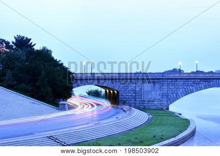 Long-exposure shot of traffic passing through short tunnel at dusk.