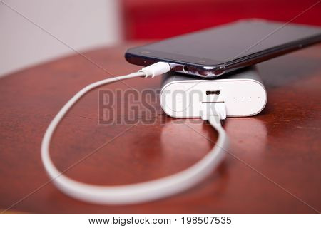 Mobile Phone Charging With Power Bank on wooden table USB cord pluged