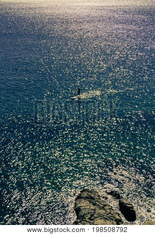 Silhouette of stand up paddle boarder paddling in ocean at Noosa in early morning Queensland Australia