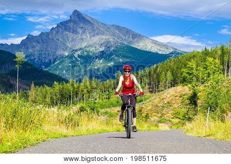 Happy woman on MTB bike on road in Ticha valley at High Tatras mountains Slovakia.