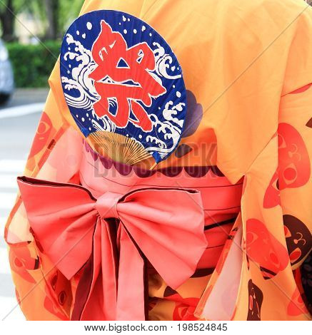 KYOTO, JAPAN - AUGUST 4, 2015 : Close-up shot of Japanese Yukata with a hand fan in summer festival. Japanese text translation is "Festival"