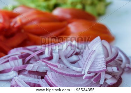 delicious piles of freshly sliced avacado tomato and onion on serving plate