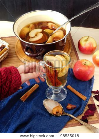 Apple compote. Female hand is holding a glass of warm compote
