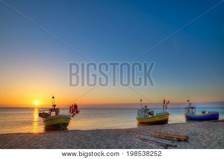 Sopot Poland June 11 2017: Sun just rises over colorful fishing cutters on sandy Sopot beach. Baltic sea Pomerania. Poland