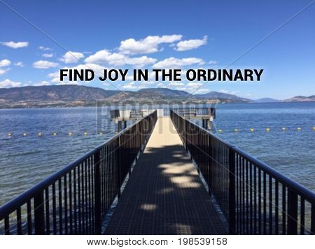 Inspirational motivational text on scenic lake and mountains landscape view with pier in foreground. Find joy in the ordinary.
