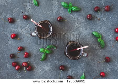 Cherry juice and fresh cherries on black background. Top view flat lay