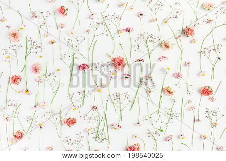 Pattern made of orange rose flowers pink gypsophila flowers and daisy flowers on white background. Flat lay top view