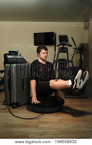 Man In Ems Suit Doing L-sit Plank On Bosu Ball