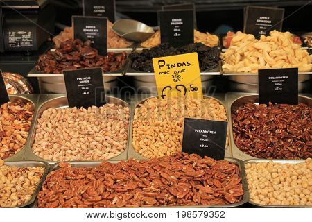 Fresh nuts on a market stall (text on tags: names and prices of various nuts in Dutchpecan nuts peanuts pistacho para and cashew)