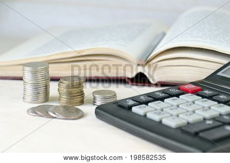 Coins Stacked Pile, Calculator, Open Book Light Background. Calculation Of Financial Stability And B