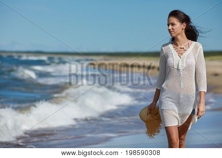 Young woman walking on white sand to beautiful beach, Baltic Sea, Poland