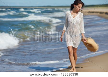 Young woman walking on white sand to beautiful beach, Baltic Sea, Poland