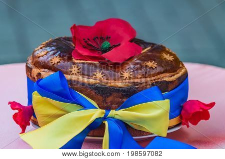 Ukrainian homemade festive bread decorated with red poppies and yellow-blue ribbon which symbolizes the Ukrainian flag