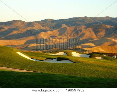 Golf Green in Front of Mountains at Sunset.