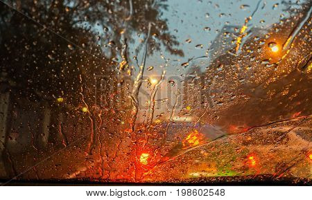 heavy raindrops and street light bokeh at night on car wind shield