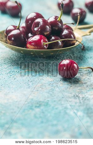 Fresh cherry in spoon over blue background. ripe cherries. sweet berries.
